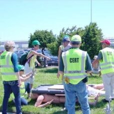 Group of people in CERT vests participating in a drill or training exercise outdoors.
