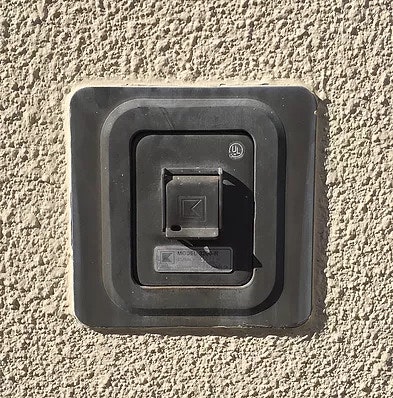 A black electrical outlet cover on a textured wall.