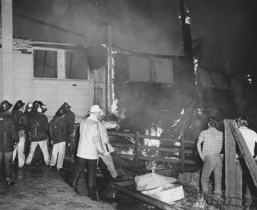 Firefighters and onlookers at a building fire at night.