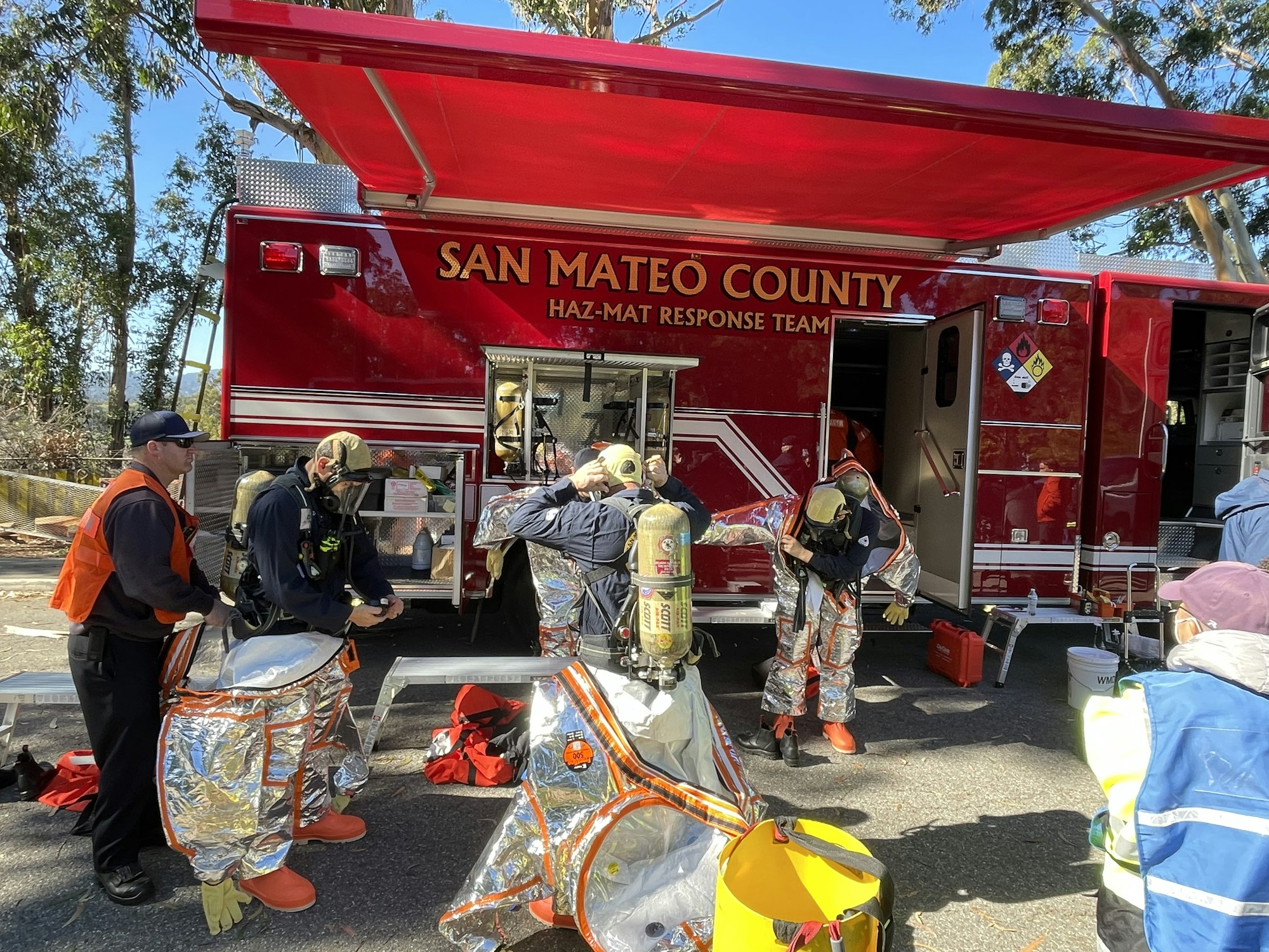 People in hazmat suits preparing equipment near a San Mateo County Haz-Mat Response Team vehicle.