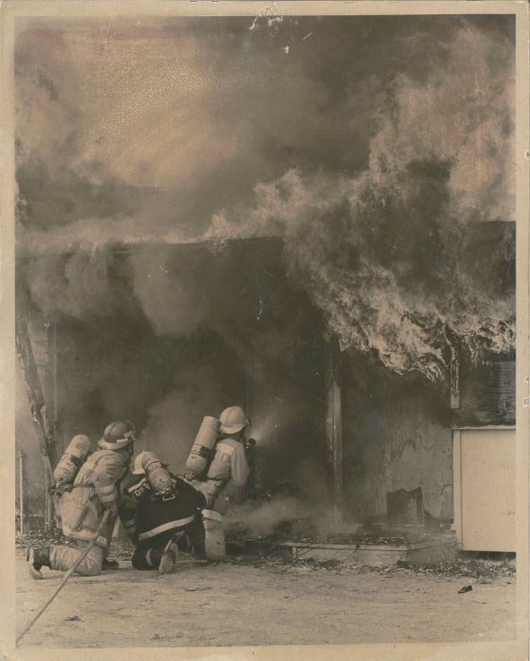 Firefighters battling a blazing building with heavy smoke and flames.