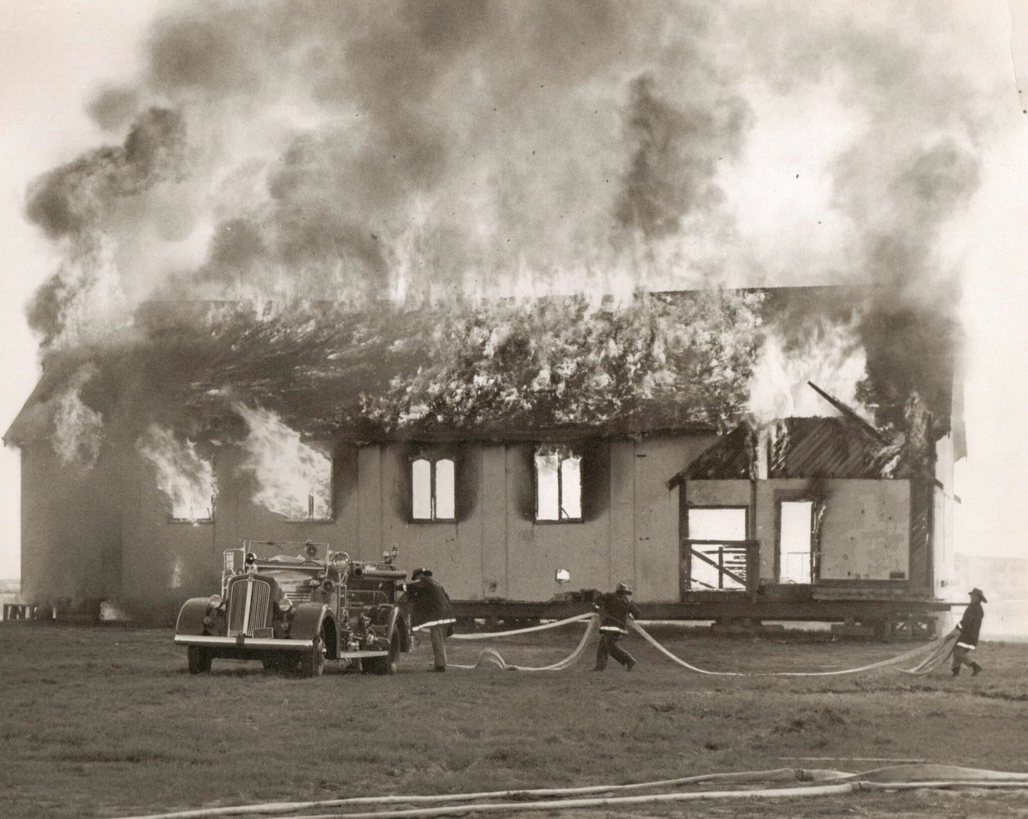 A building on fire with firefighters and a fire truck in action.