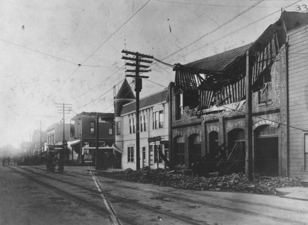 Street scene with damaged buildings, debris, and power lines.