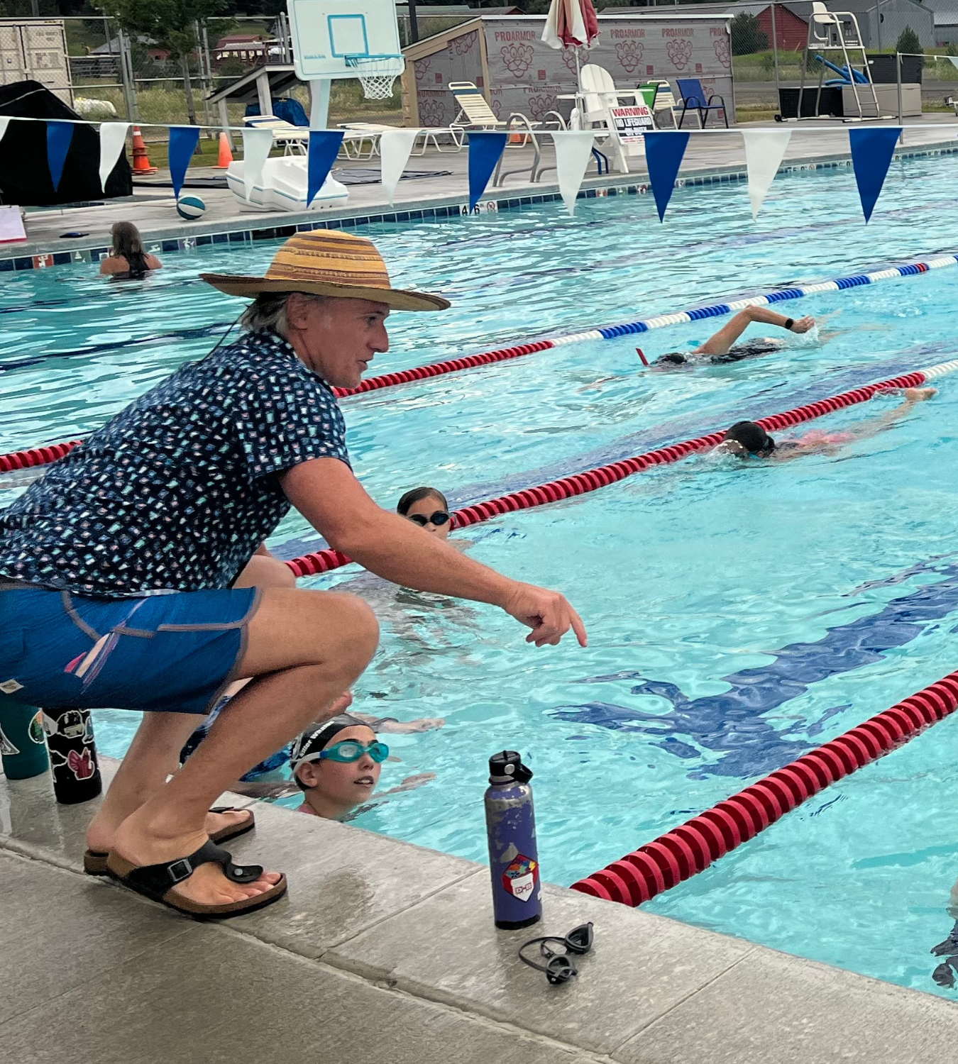 May contain: water, clothing, hat, chair, furniture, person, footwear, sandal, leisure activities, sport, swimming, water sports, accessories, glasses, pool, swimming pool, and shorts