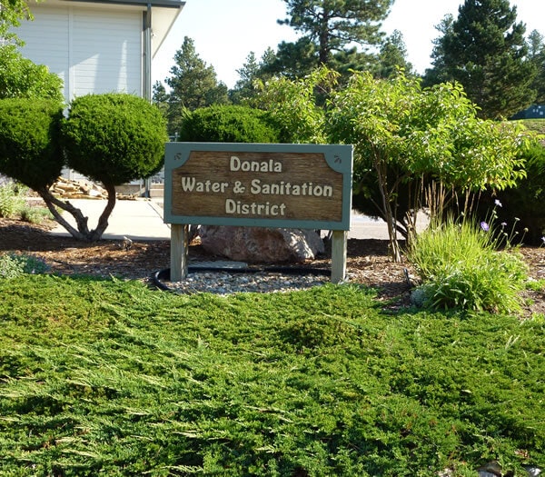A sign reading "Donala Water & Sanitation District" surrounded by greenery.