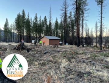 A cabin in a forested area with workers visible, likely engaged in fire safety or land management activities.