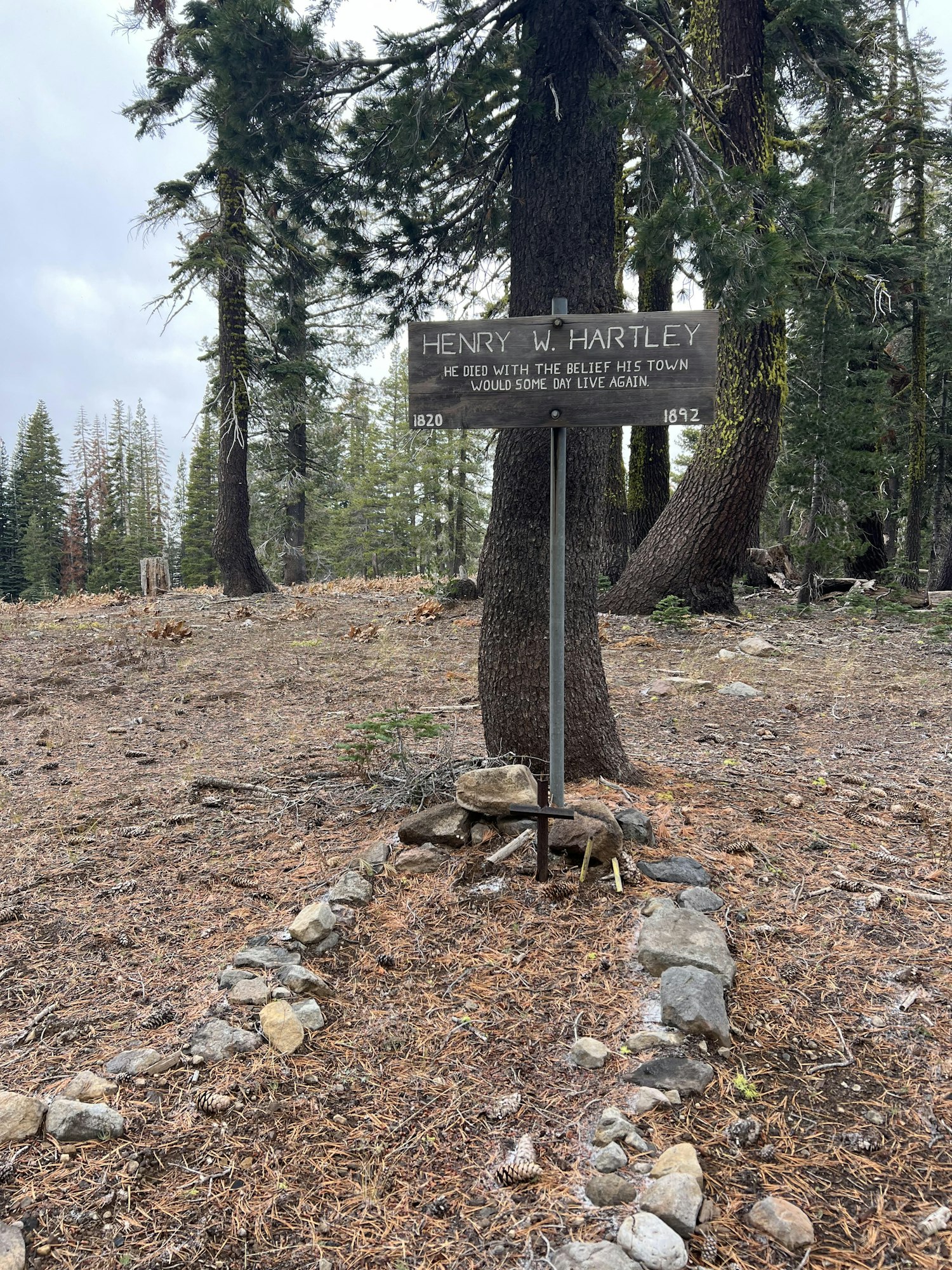 A memorial sign for Henry W. Hartley (1820-1892) among trees with the belief that his town would live again.