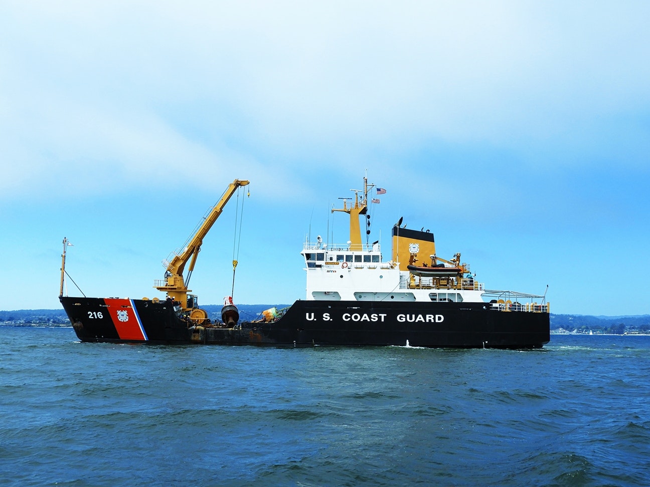 A U.S. Coast Guard ship at sea with a crane on deck.