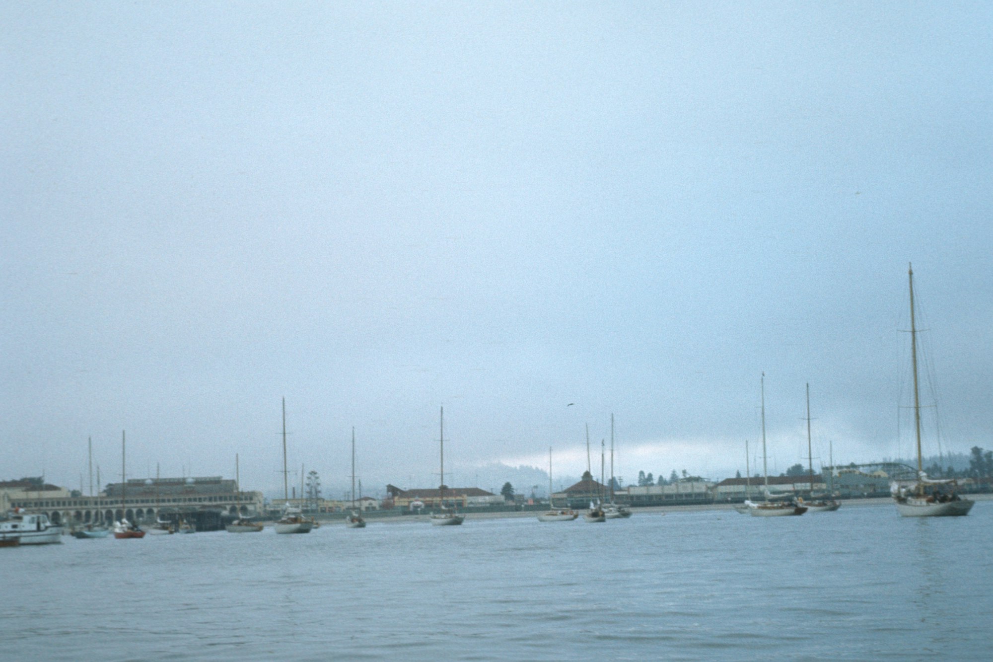 A foggy harbor scene with boats and a pier.
