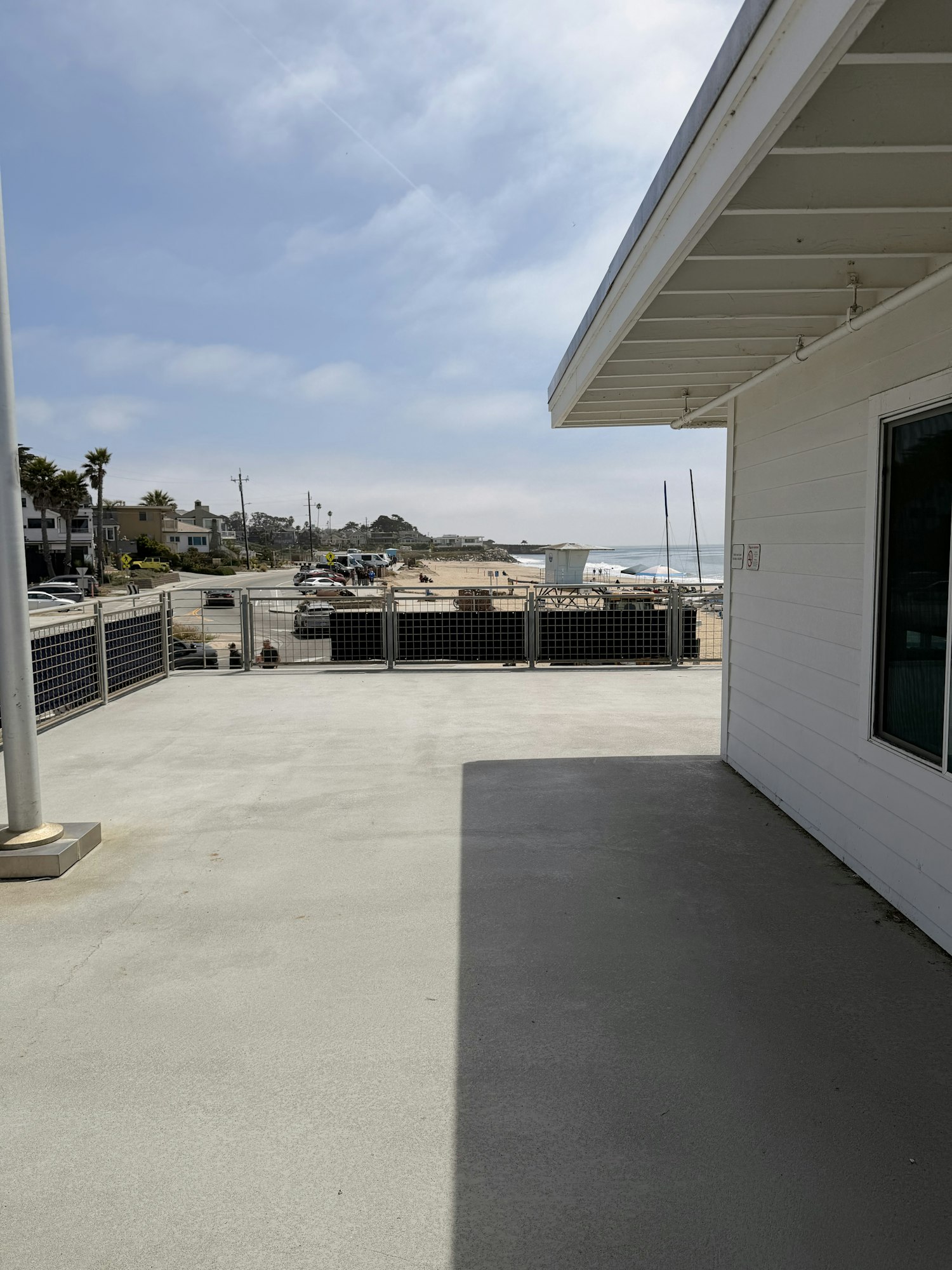 An outdoor view showing a patio, boats in the distance, and a cloudy sky, with a building in the foreground.