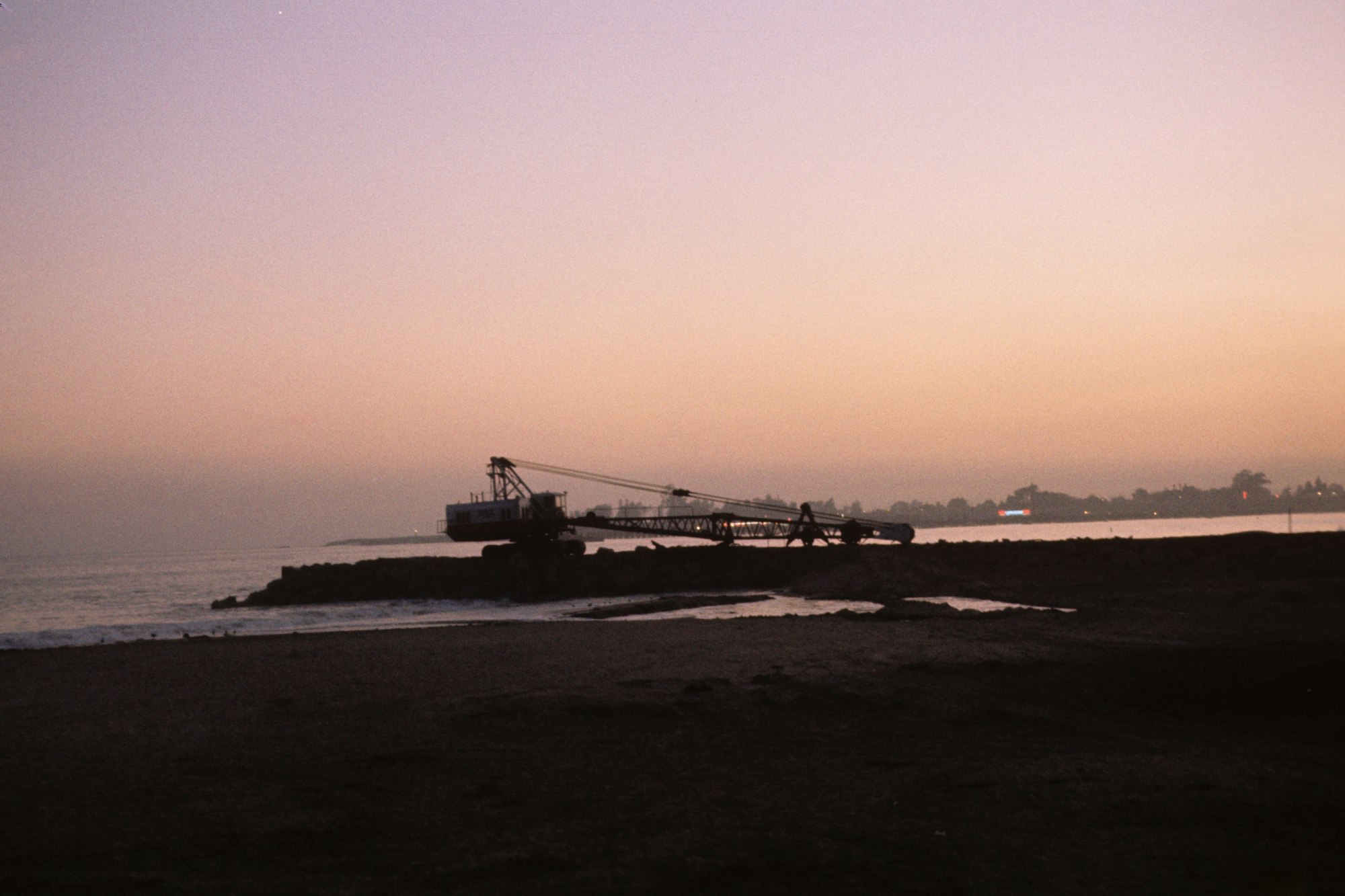 A dredger on a beach at dusk.