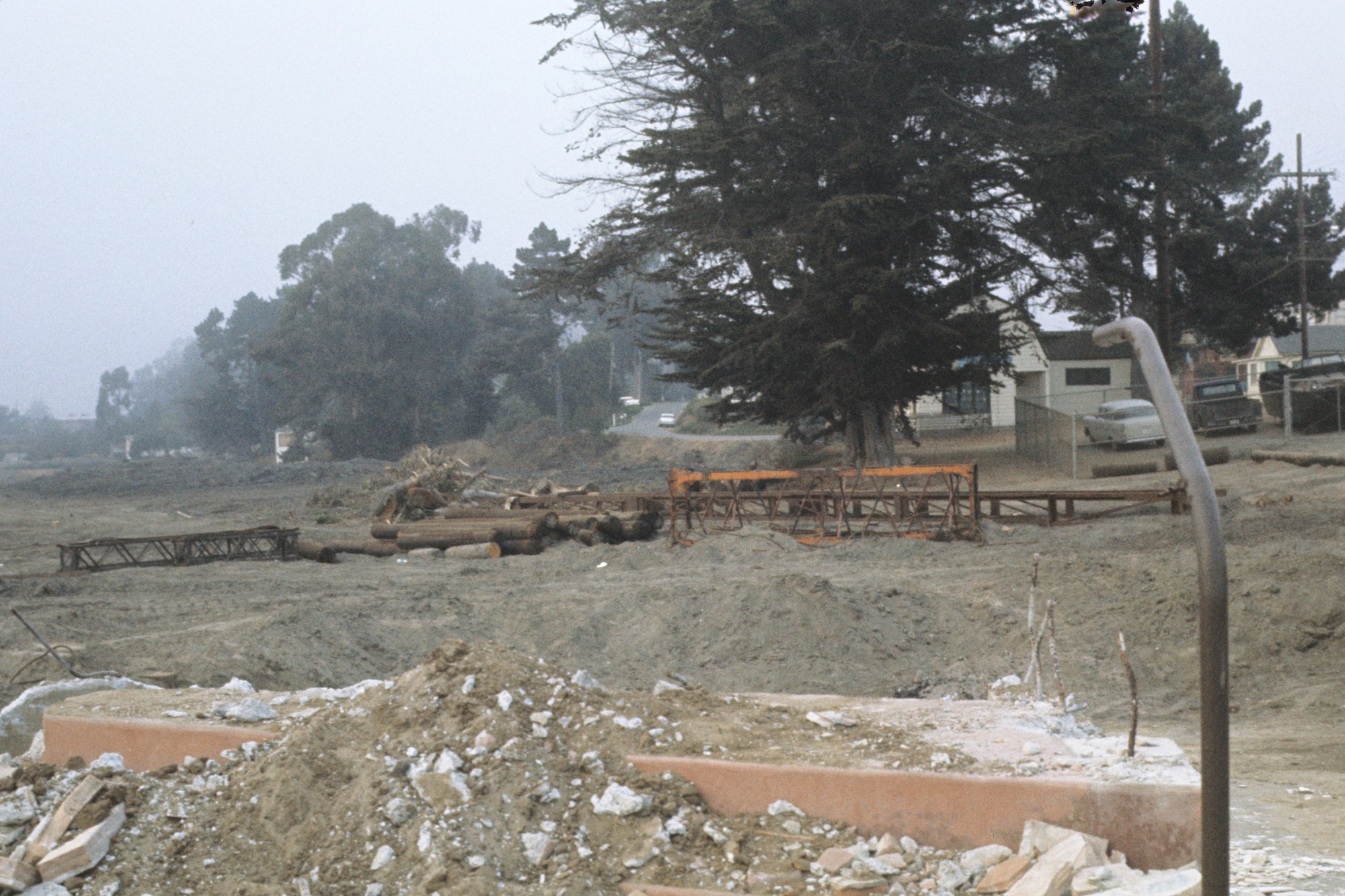 A construction site with debris, a broken water fixture, and logs.