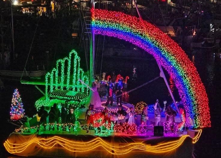 A boat decorated with colorful lights, featuring a rainbow and a cityscape display.