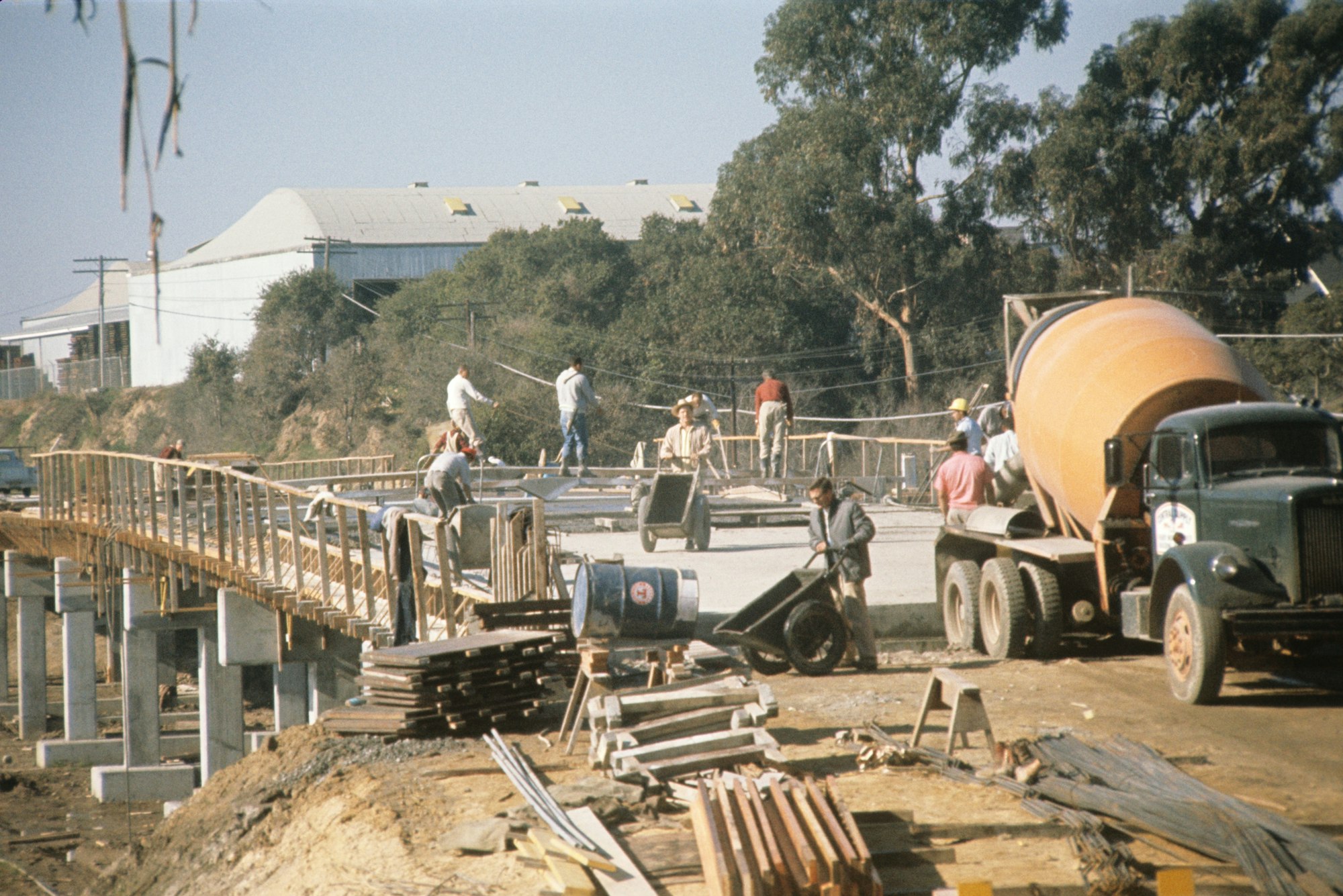 Construction workers pouring concrete with a cement mixer truck, working on a structure's foundation.