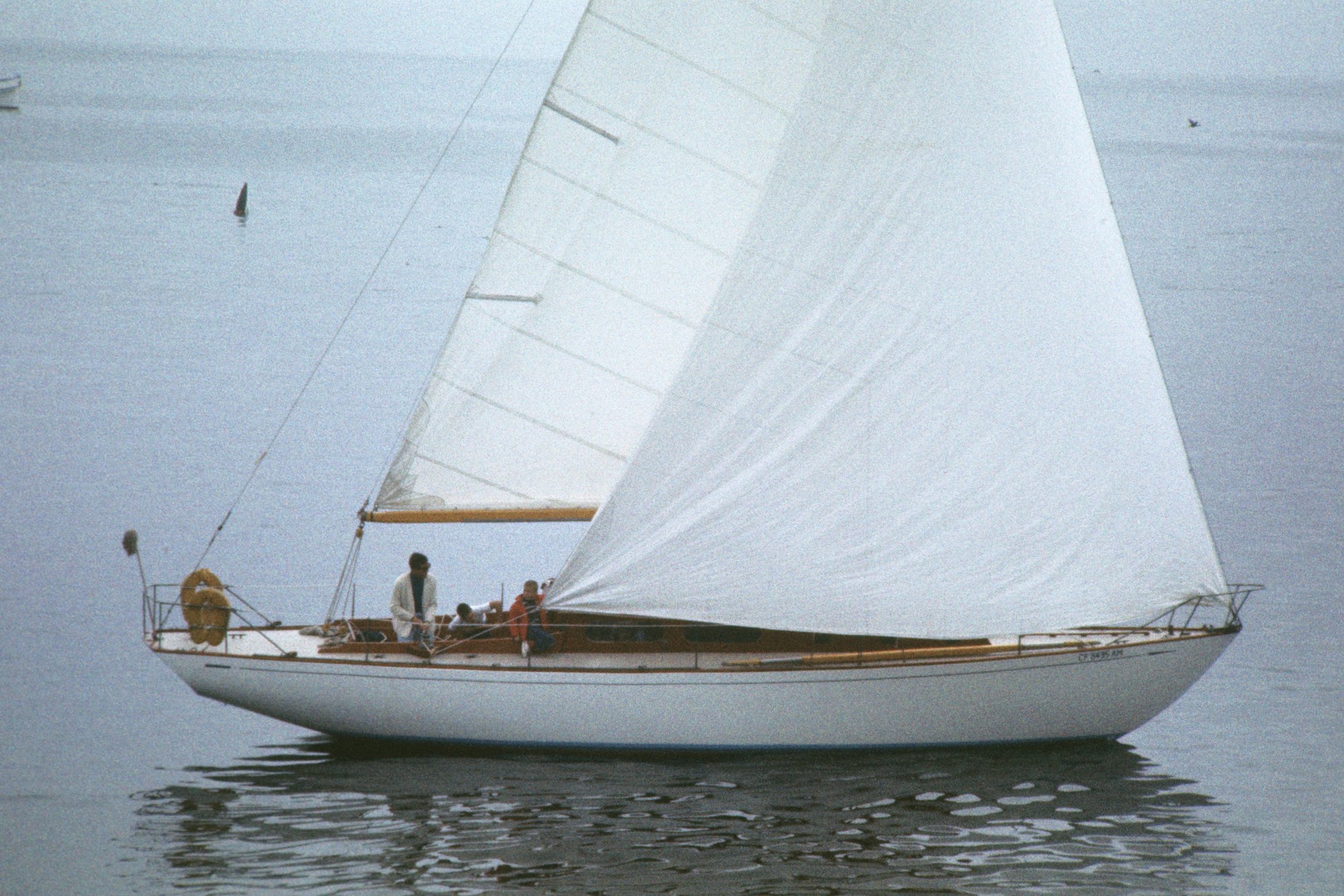 A sailboat on calm water with passengers aboard.