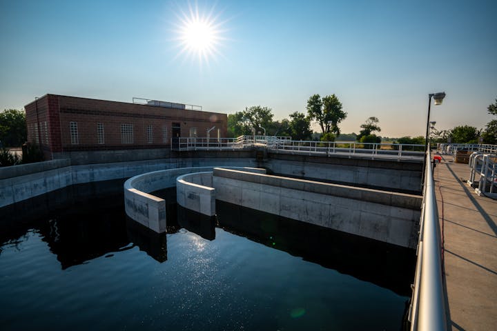 A water treatment plant with concrete structures under a bright sun.