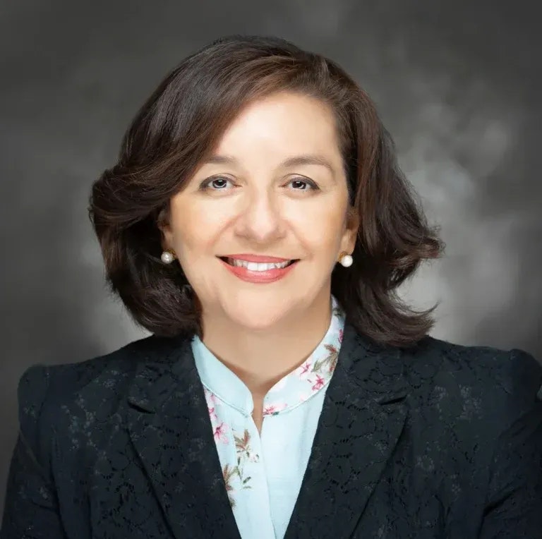 The image features a smiling woman with dark hair, dressed in a stylish outfit, against a neutral background.