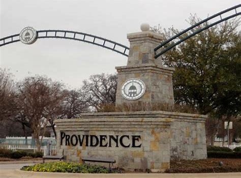 Stone entrance sign reading "PROVIDENCE" with archways and trees in the background.