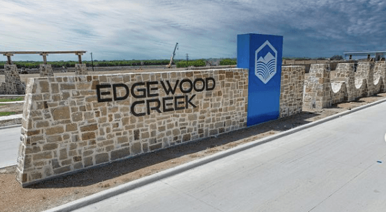 Stone entrance sign for "Edgewood Creek" with a blue column featuring a logo.
