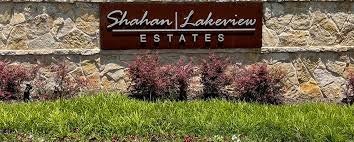 Sign reading "Shahan Lakeview Estates" on a stone wall with grass and shrubs.