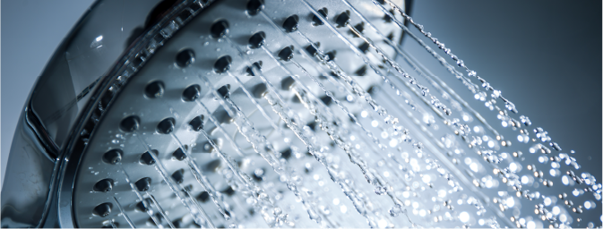 A close-up of a showerhead with water cascading down, showcasing the flow and spray of water droplets.
