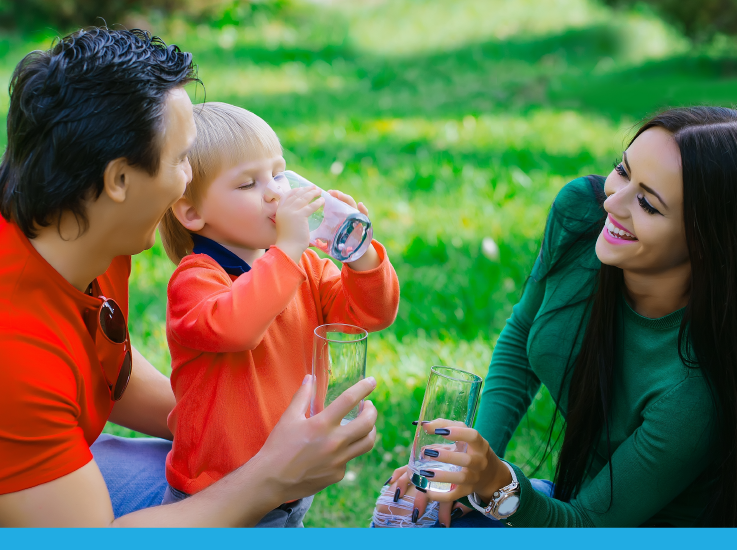 A family enjoys a sunny day outdoors, drinking beverages and sharing joyful moments together.