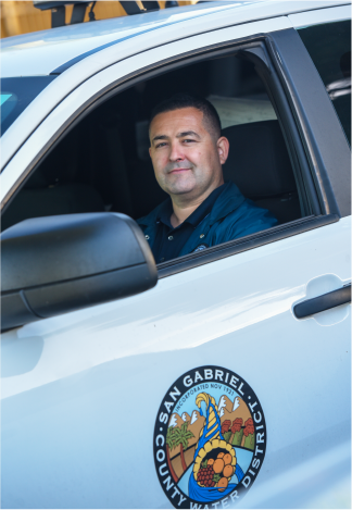 A person sits in a vehicle marked with the San Gabriel County Water District logo.