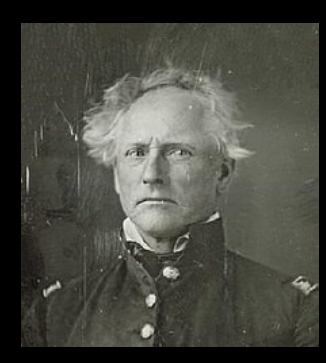 A stern-looking older man with disheveled hair wearing a formal military uniform in a vintage photograph.
