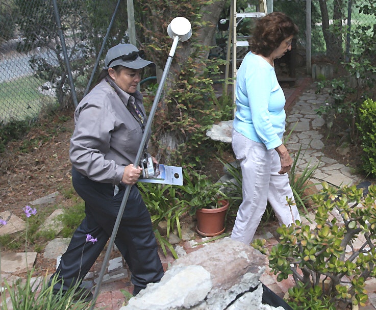 A District employee walks with a resident during a backyard mosquito inspection.