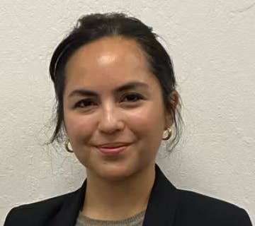 The image features a woman smiling, wearing a black blazer and hoop earrings, with a textured white background.