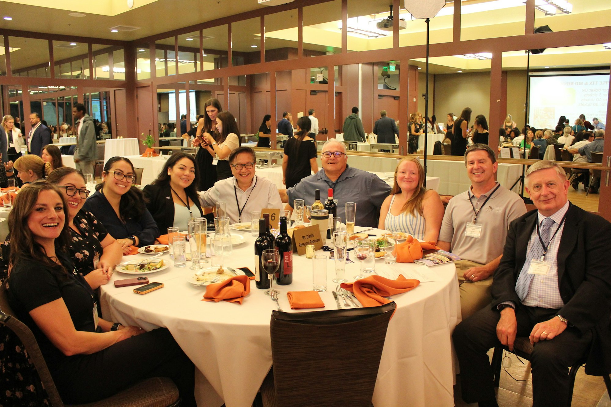 A group of eight people smiling and posing at a round table during a formal event.