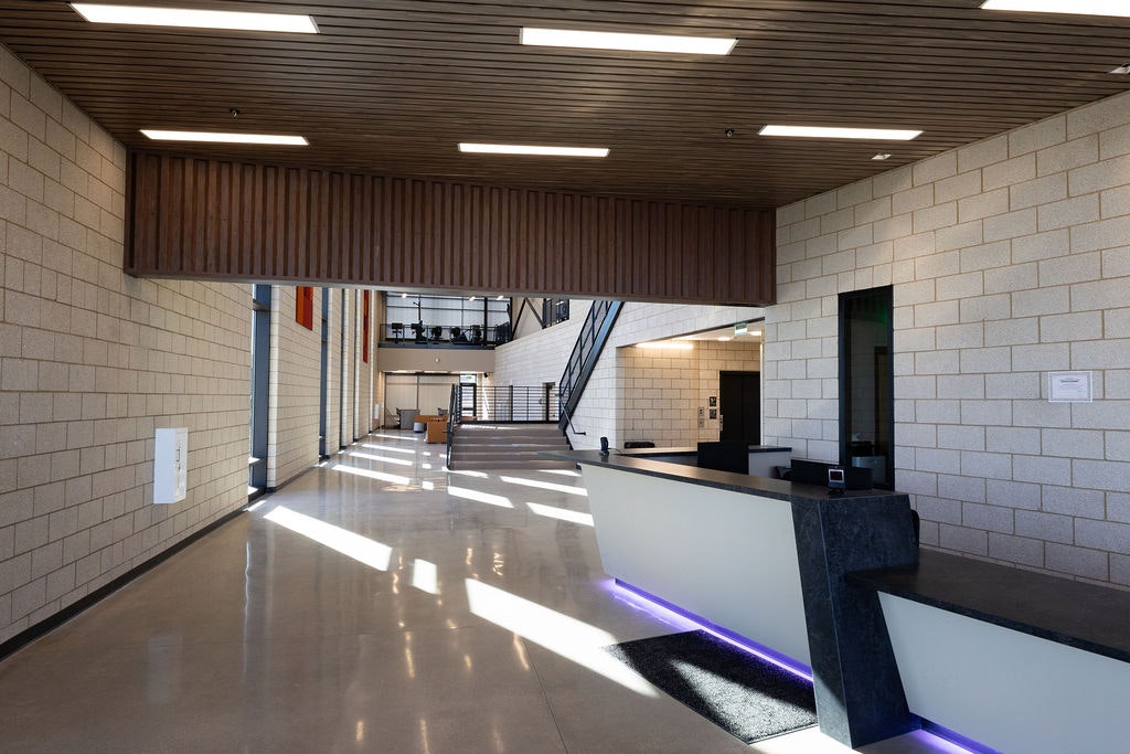 A modern, spacious lobby with sleek design, large windows, a reception desk, and natural light streaming through.