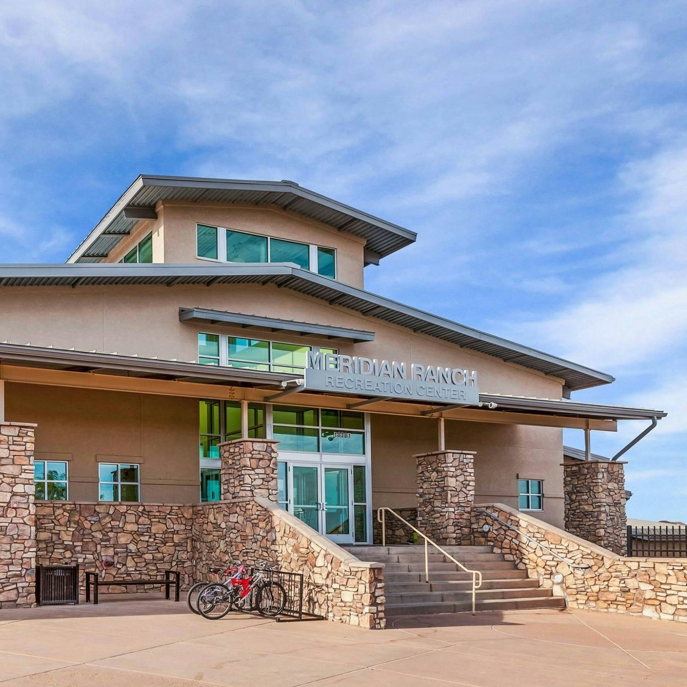 The image shows a modern recreation center named "Meridian Ranch," featuring a stone facade and a staircase entrance.