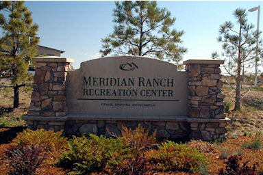 A stone sign for the Meridian Ranch Recreation Center, featuring landscaping with shrubs and trees.