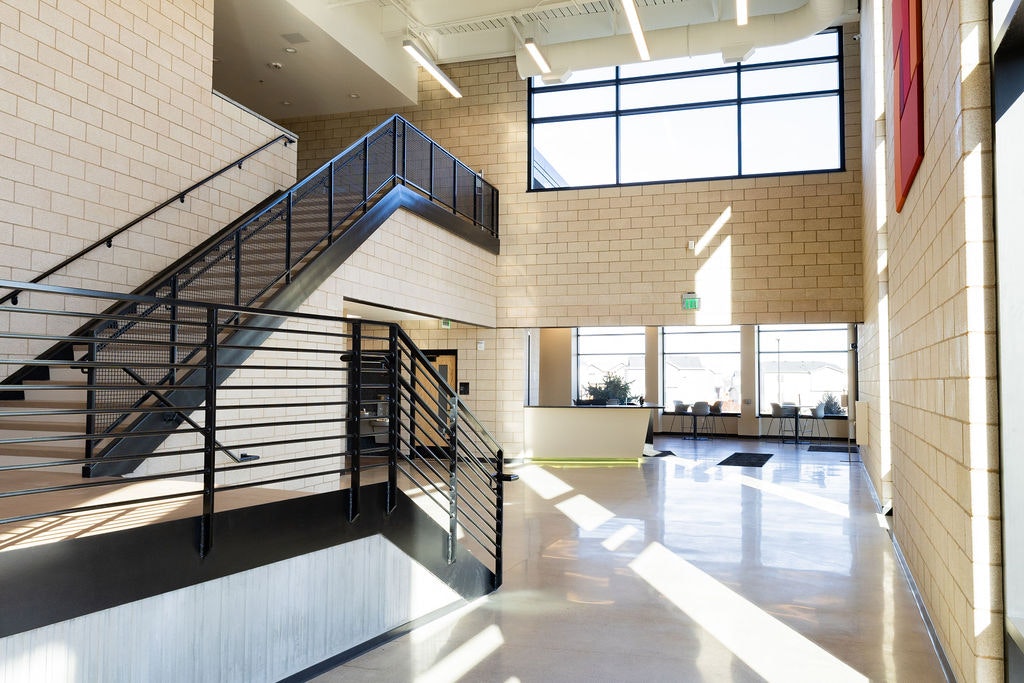 A bright, modern interior space featuring a staircase, large windows, and minimalist design elements.