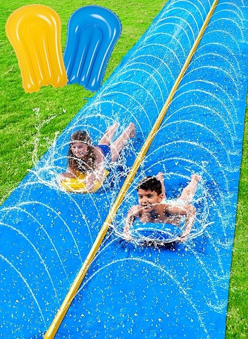 Kids sliding on a blue water slide with splash effects. Inflatable cushions seen above.