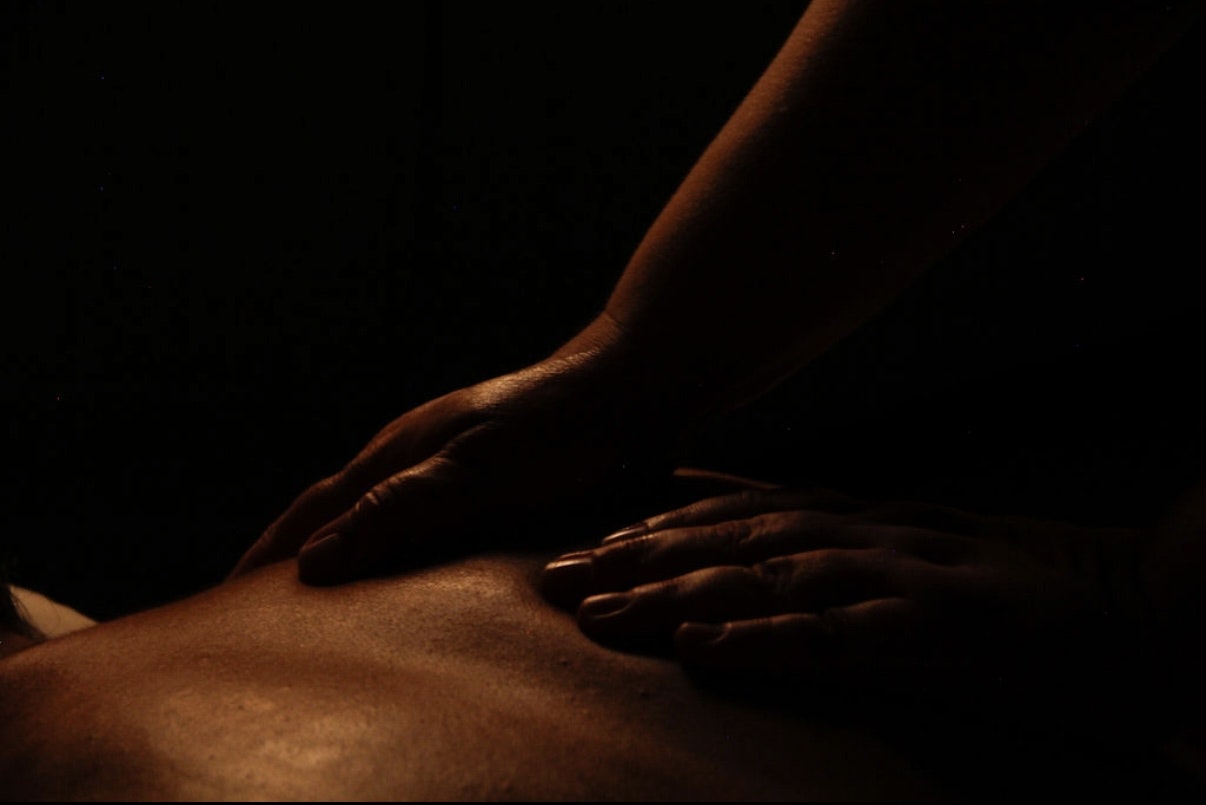 A person receiving a massage with dim, warm lighting accentuating the hands.