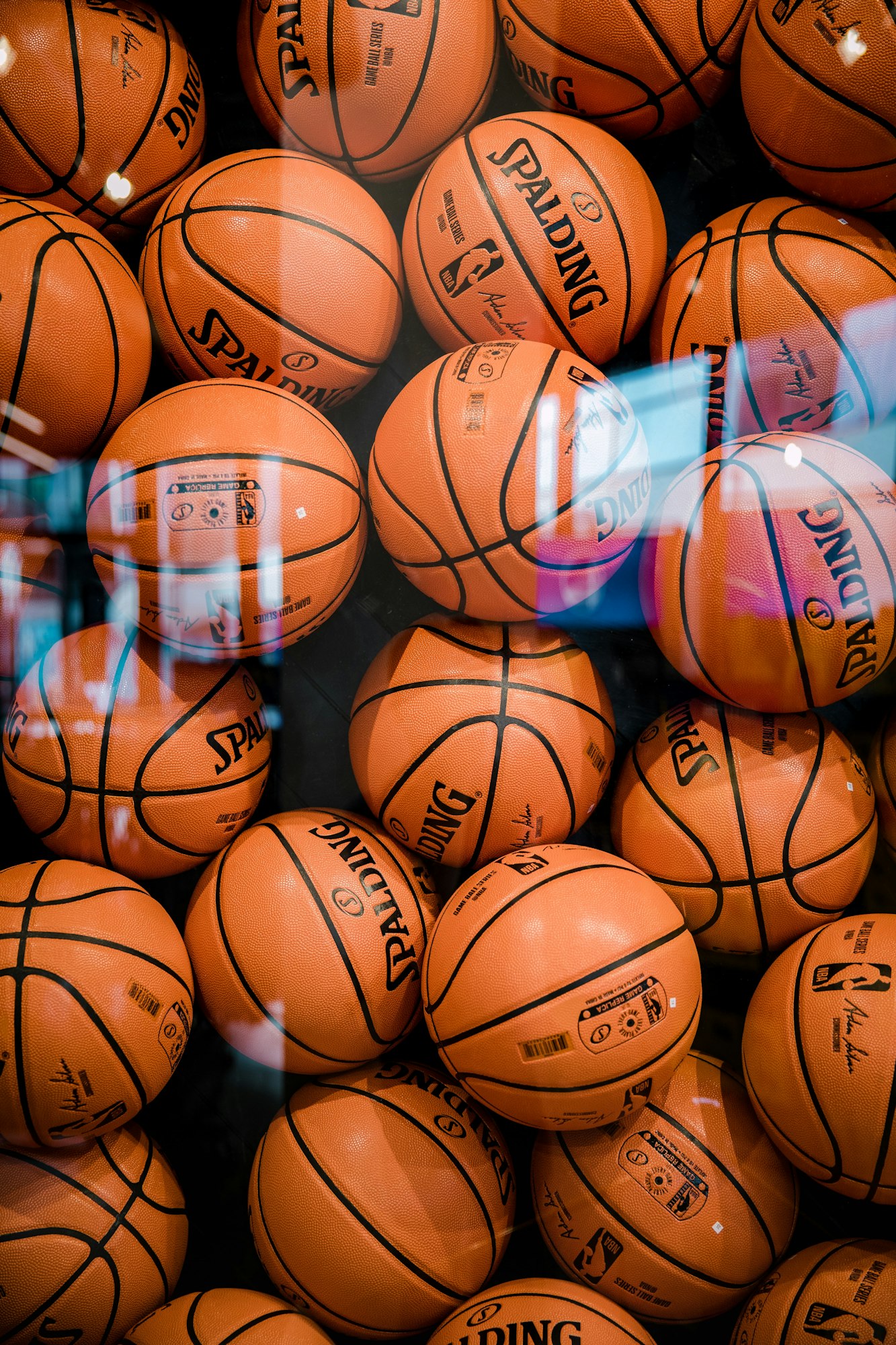 A pile of Spalding basketballs with NBA branding, reflecting light.