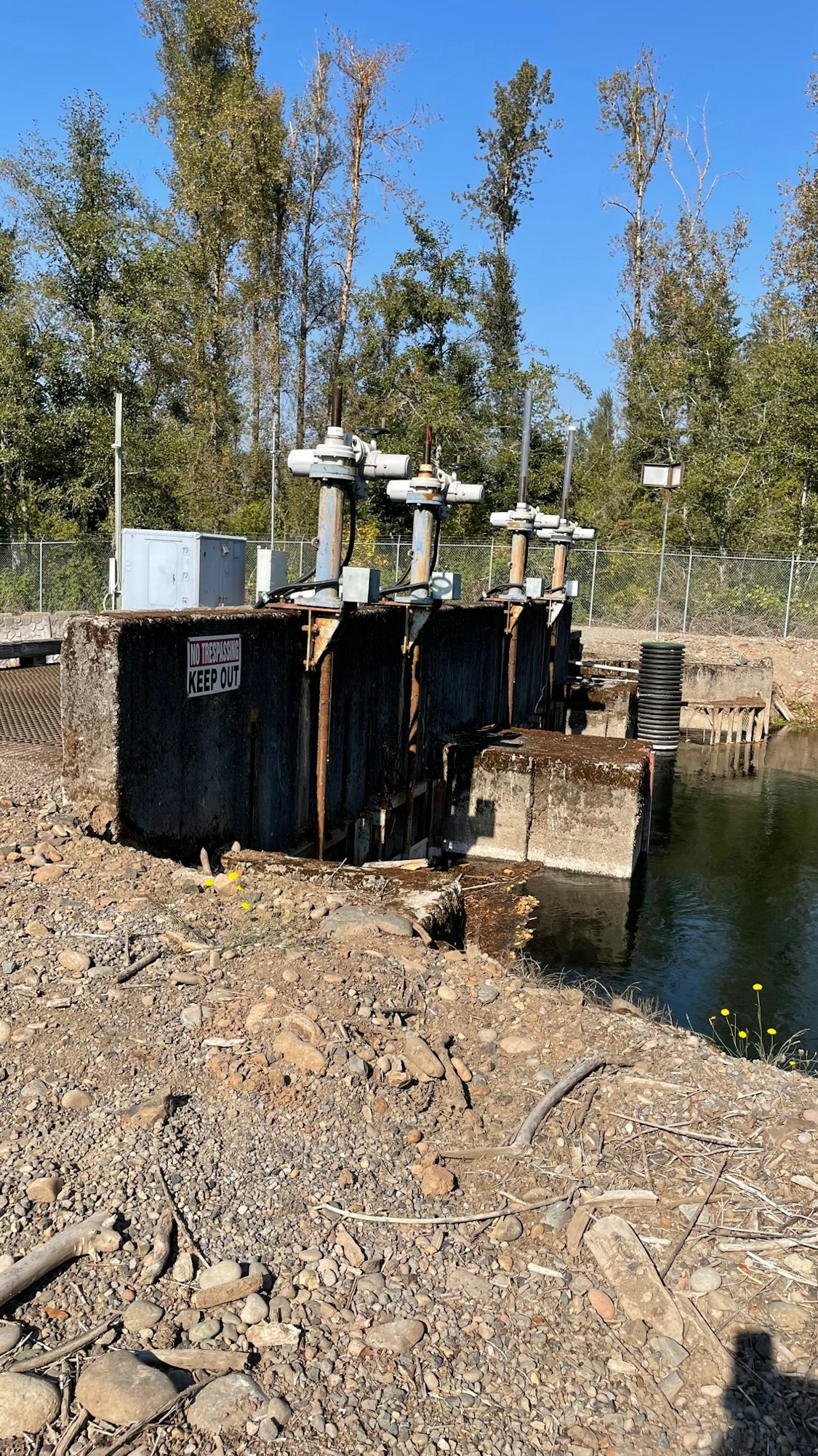 Industrial equipment by water with warning signs.