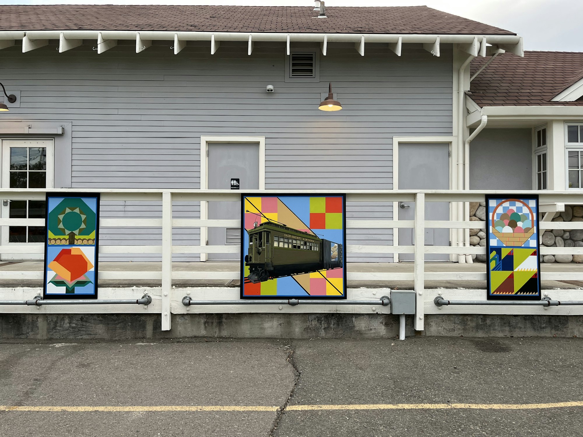 A building with railings featuring three colorful, geometric art banners.