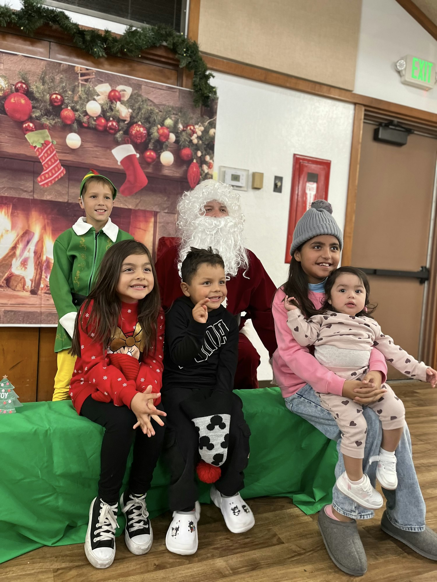 A group of children pose with Santa in festive attire and setting.