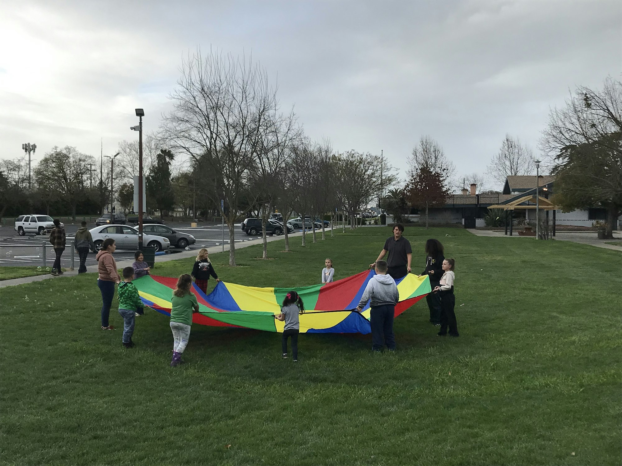 People playing with a colorful parachute in a park.