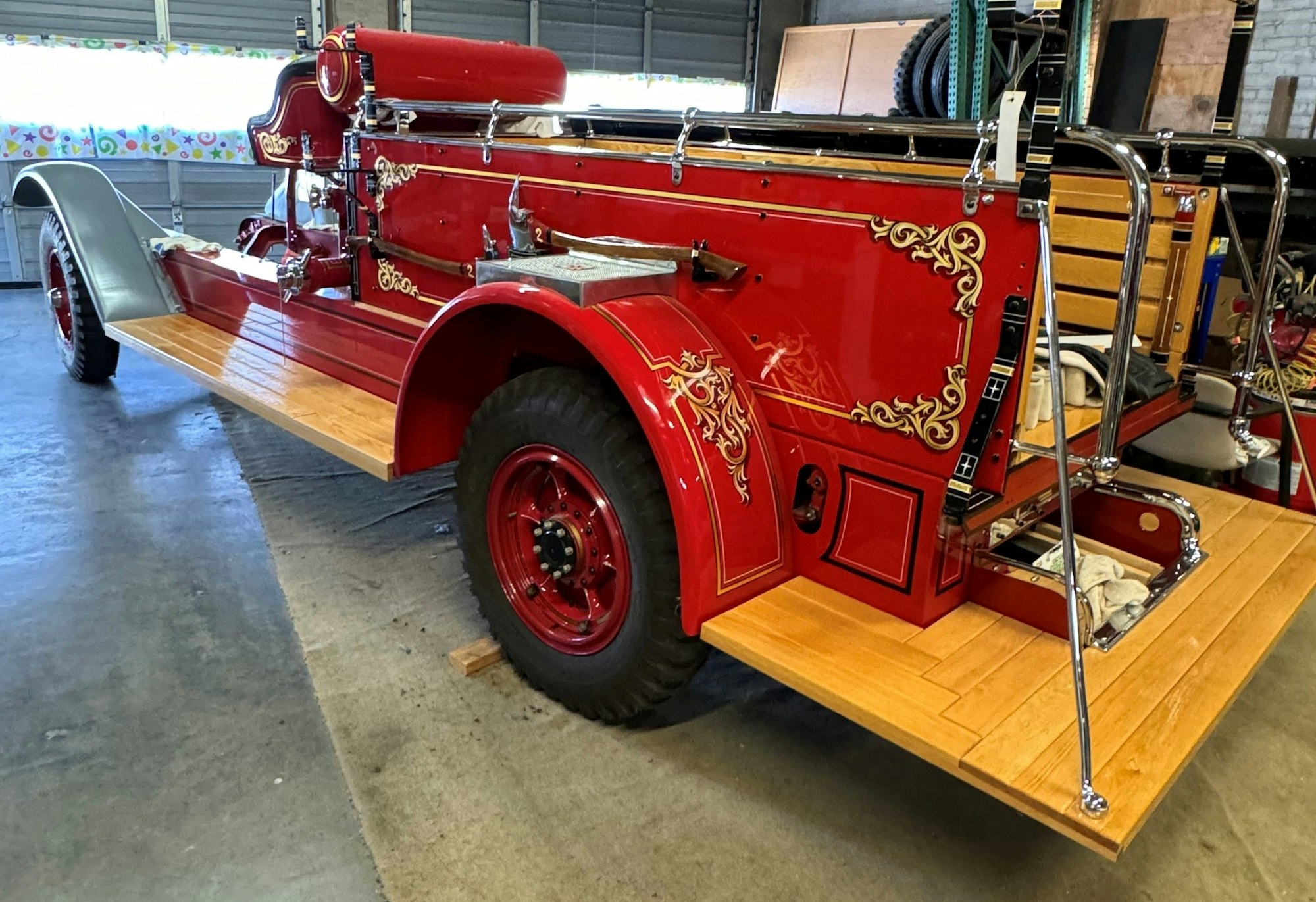 A vintage red fire truck with decorative gold details, in a garage setting.