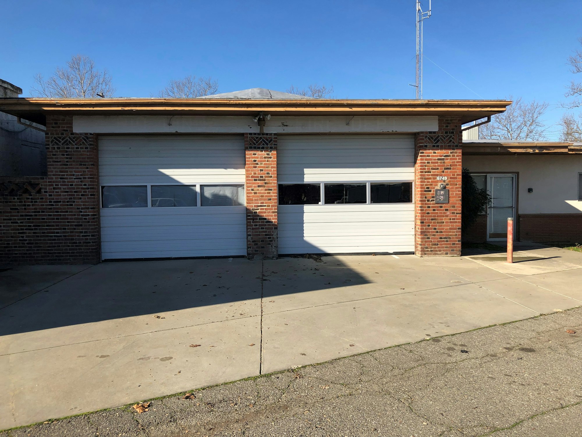 A brick building with two white garage doors and a glass entrance on the right.