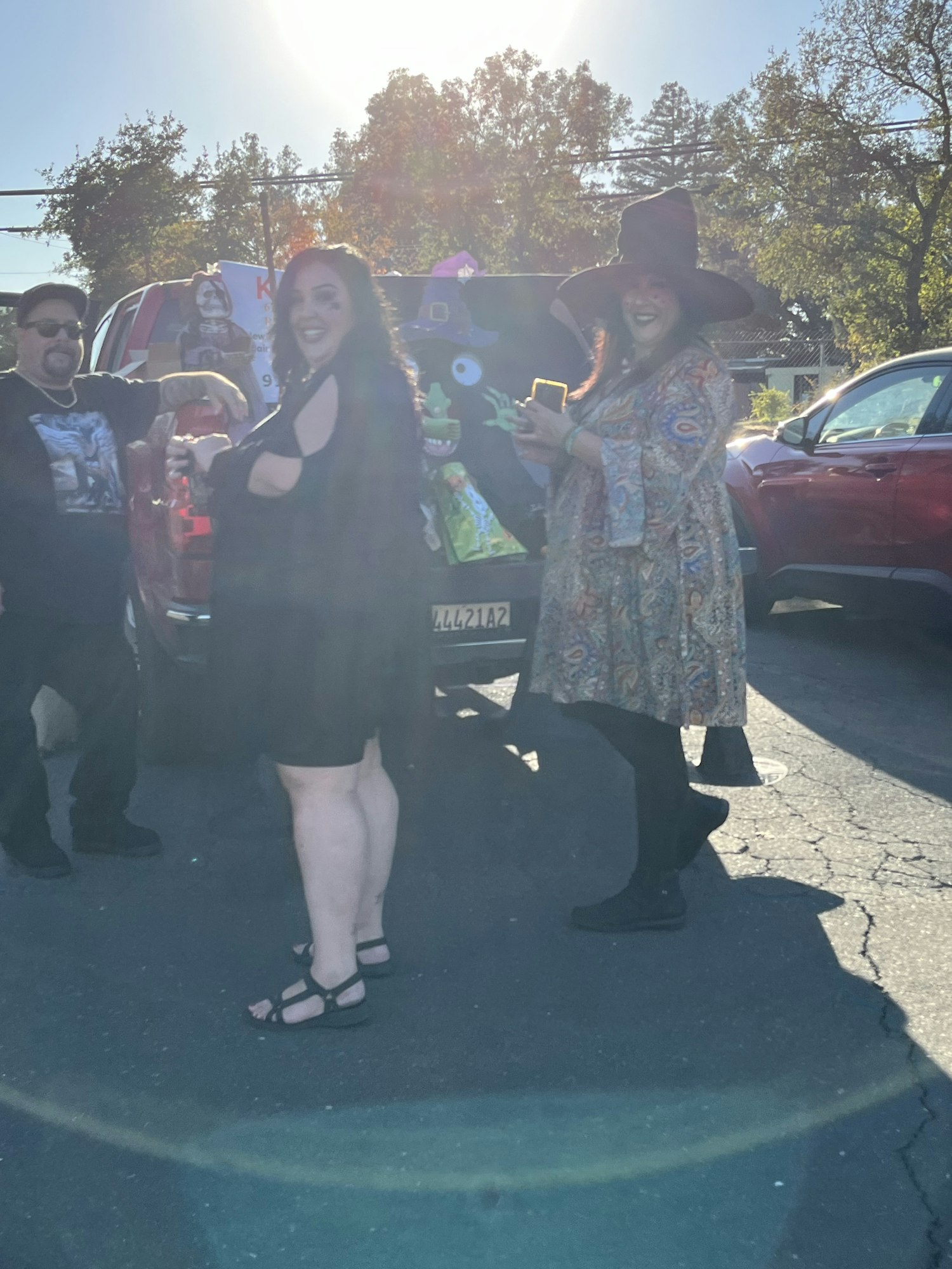 People in costumes standing in a parking lot with Halloween decorations.