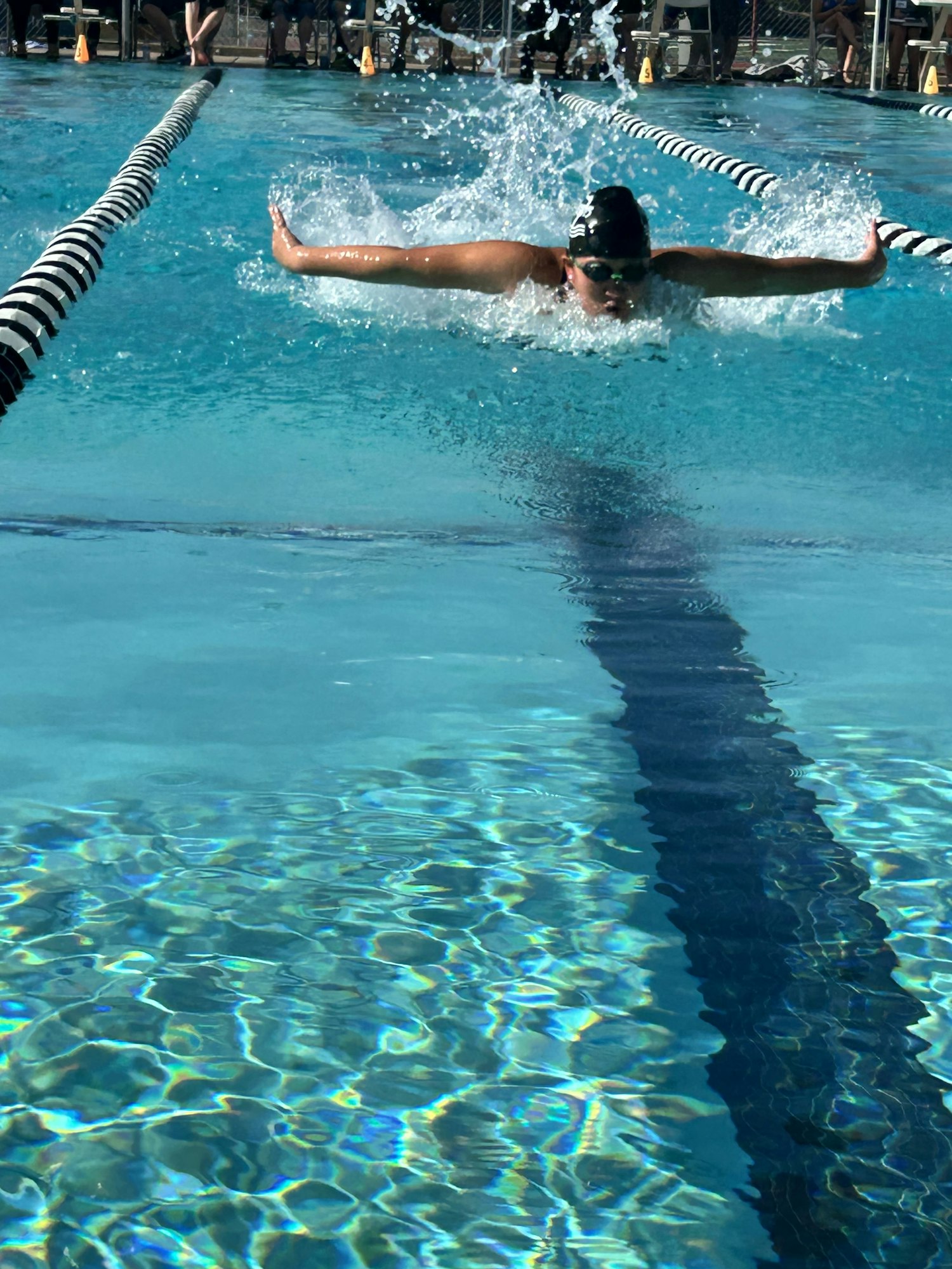 Swimmer performing a butterfly stroke in a pool, splashing water.