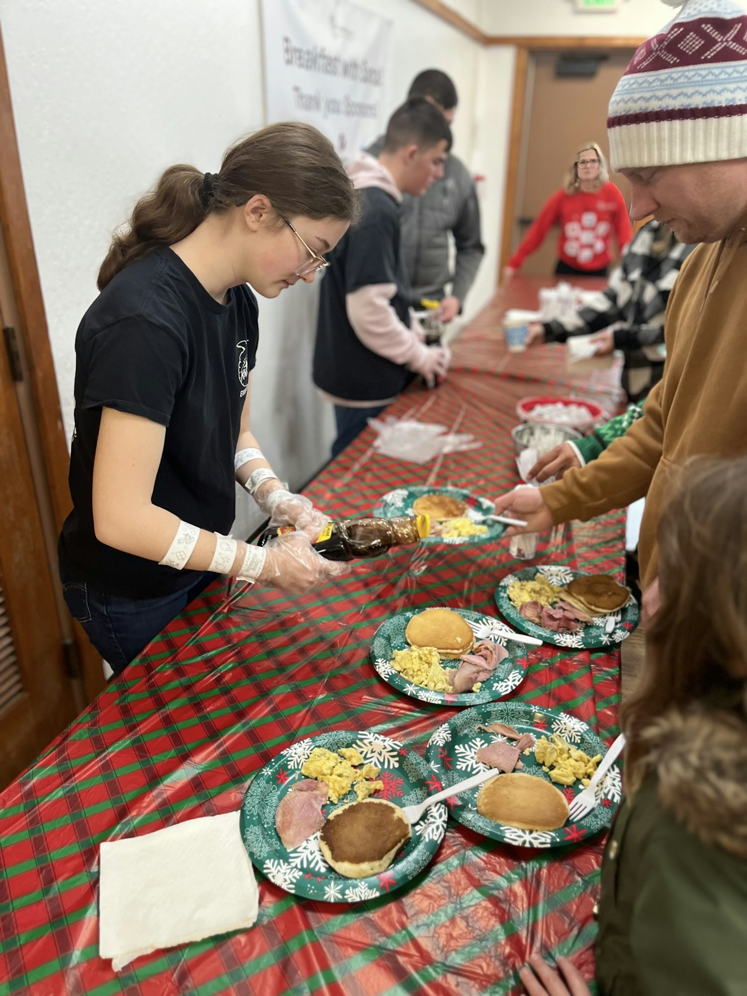 People serving breakfast on festive plates at an event.