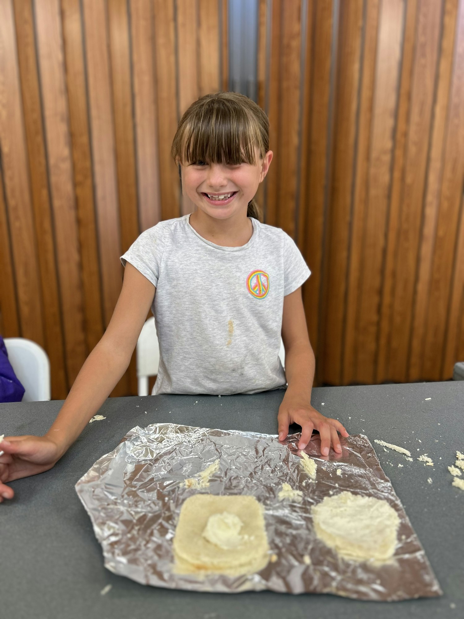 A smiling child with dough on foil, likely engaging in a cooking or baking activity.
