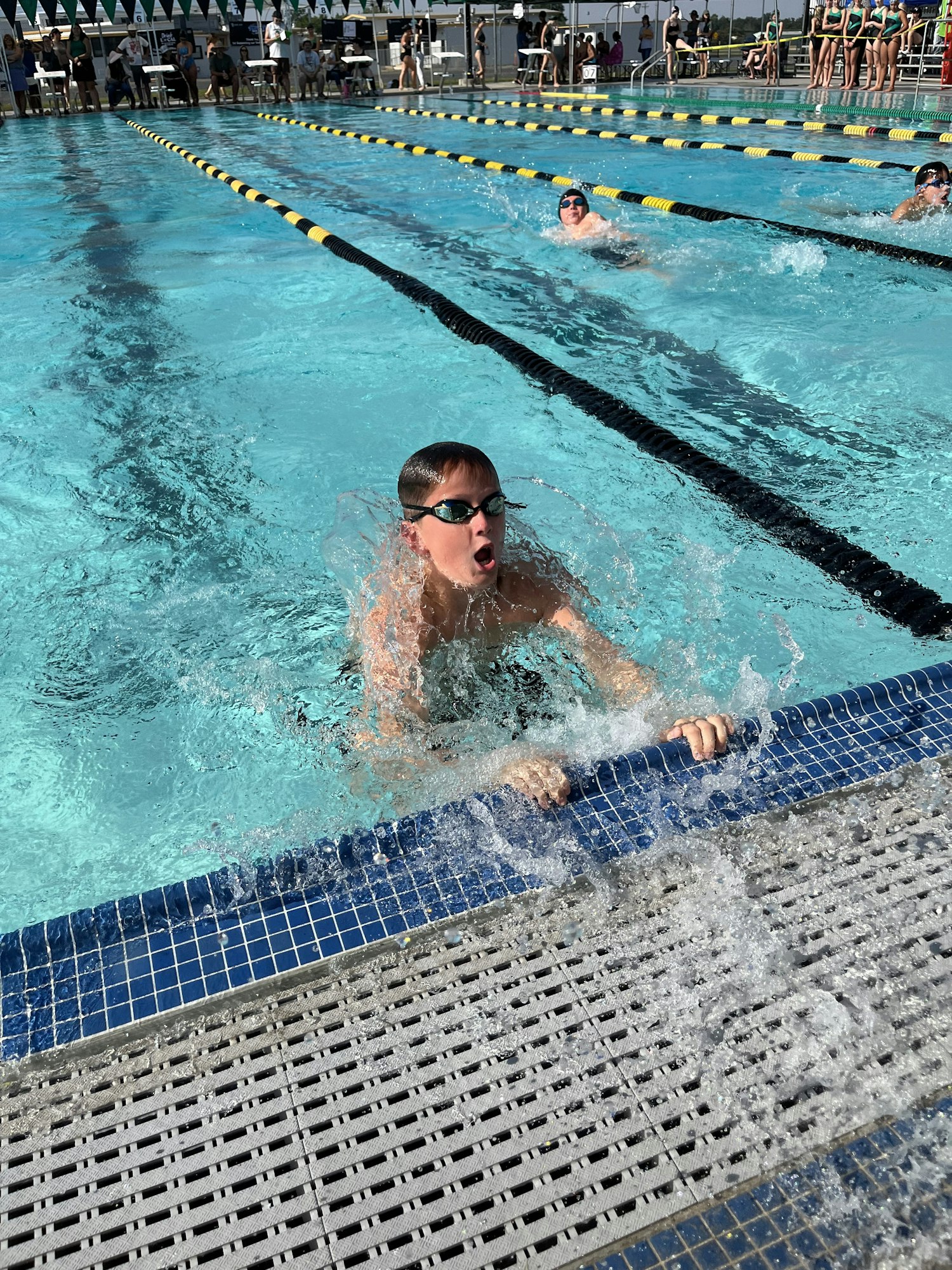 A swimmer reaches the pool edge, splashing water, during a race in a swimming competition.
