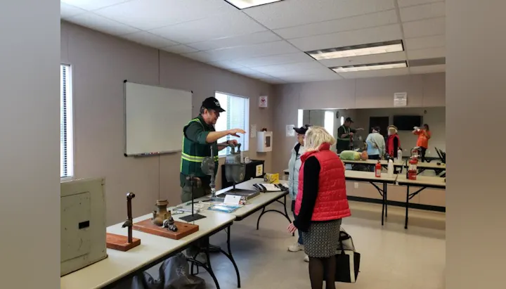People in a room discussing or demonstrating equipment on tables.